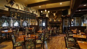 A restaurant interior with wooden tables and chairs, a stone fireplace, and a sign reading "HARRIS FARMS INC."