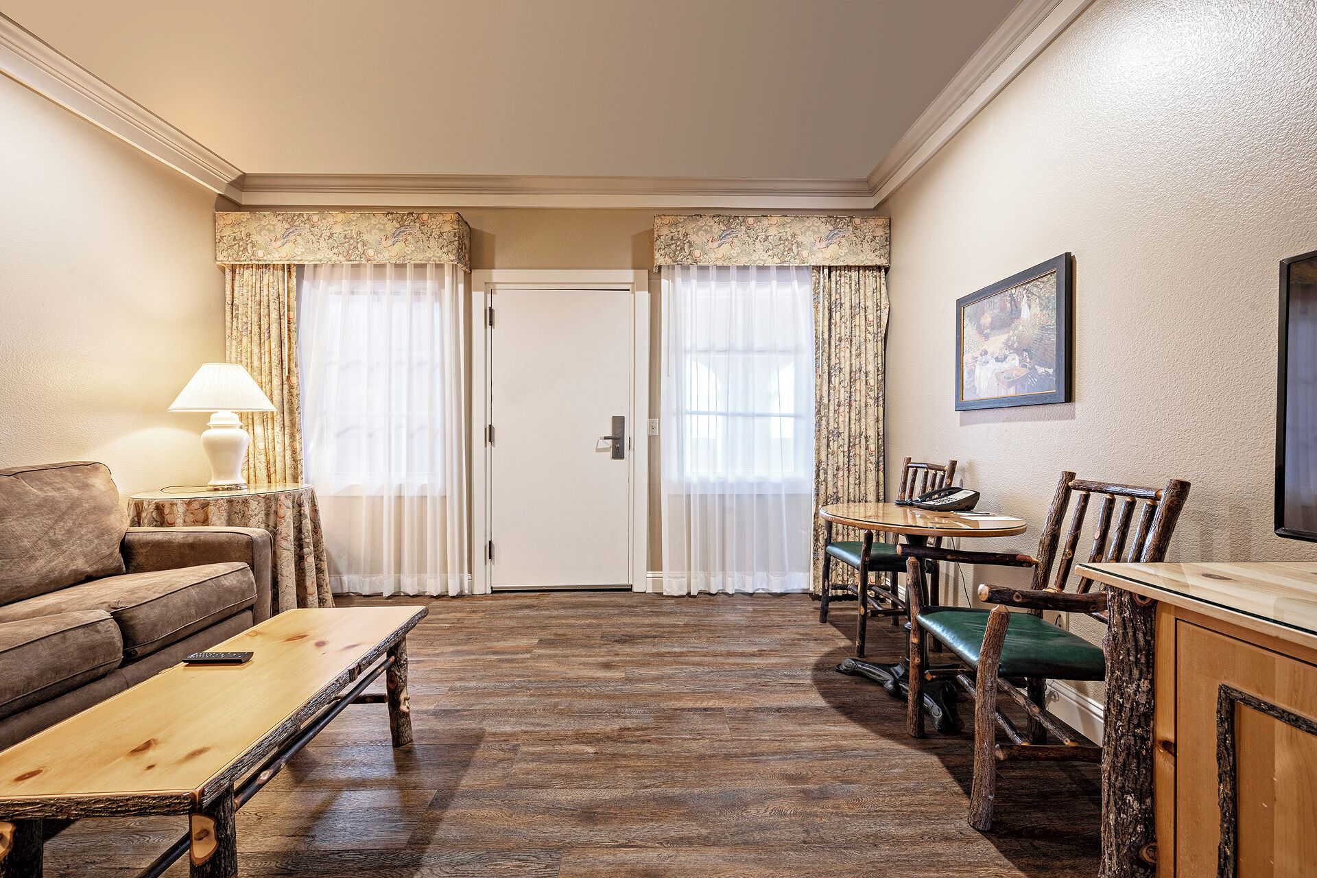 A room with a sofa, a wooden table, a dining table with chairs, and a door with curtains.