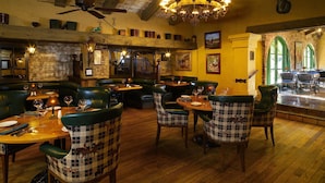 Un restaurante con suelos de madera, asientos tapizados en verde y un candelabro.