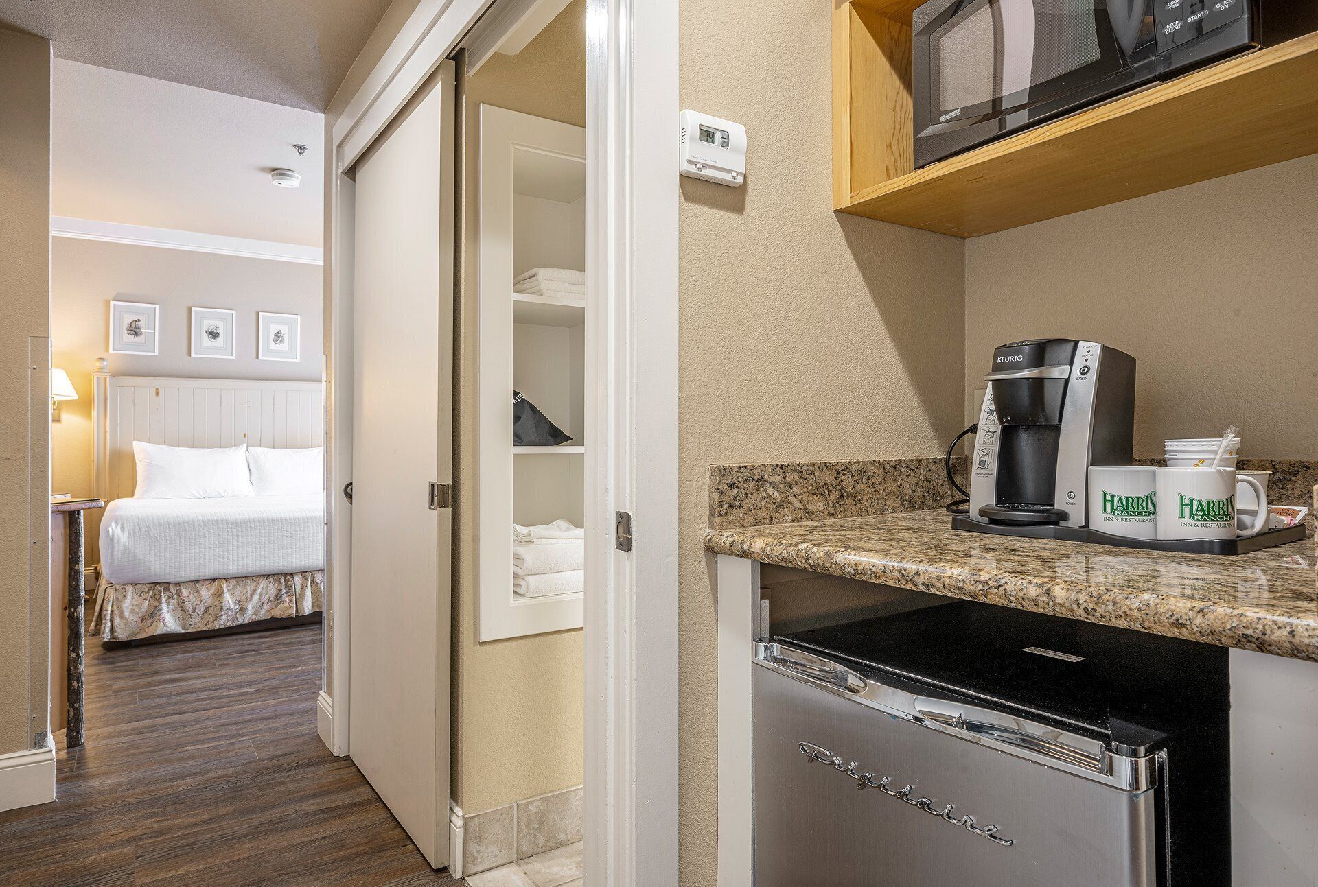Een hotelkamer met een bed, een kledingkast, een kitchenette met koffiezetapparaat en een magnetron.