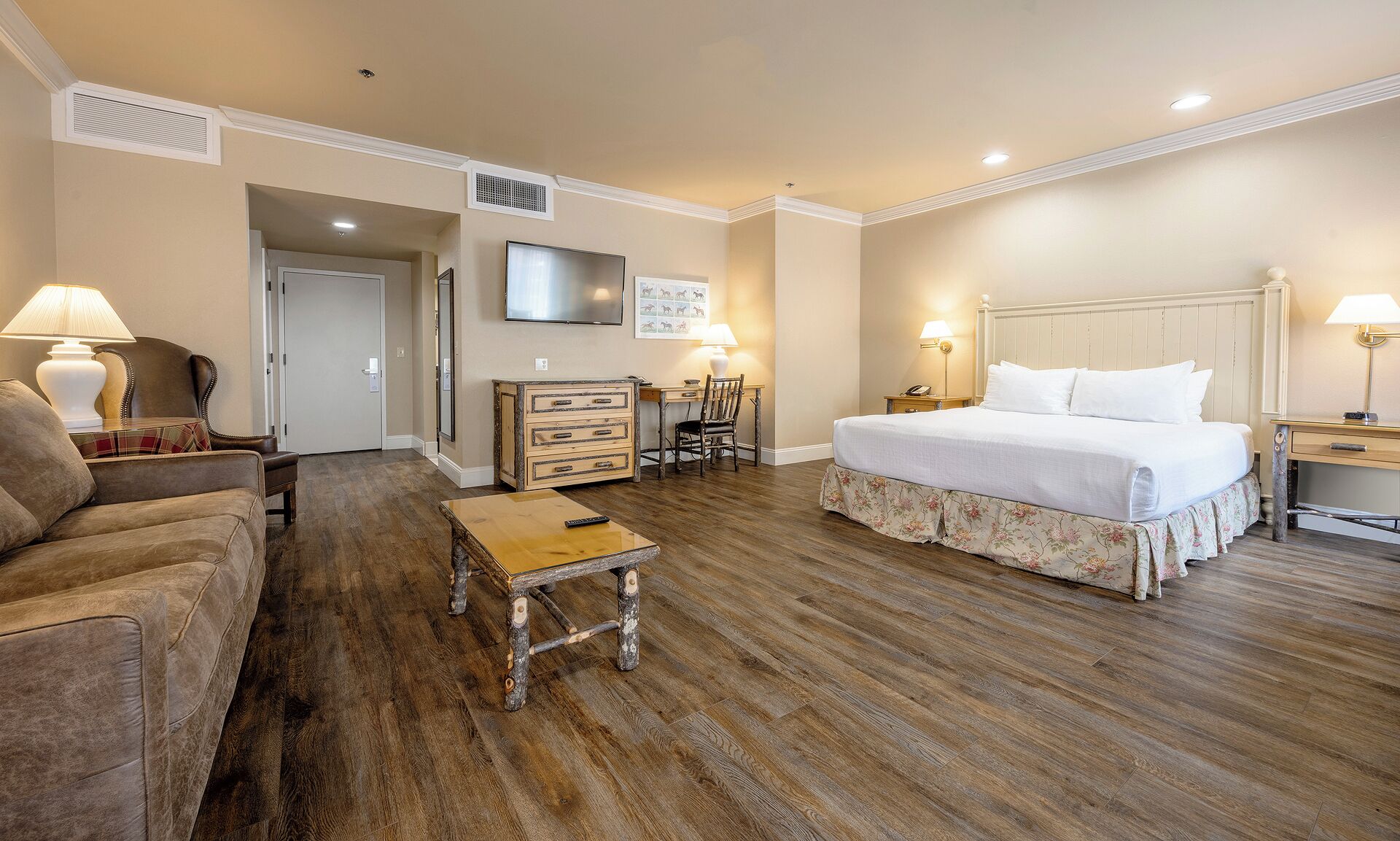A hotel room with a bed, a sofa, a desk, and a chair.