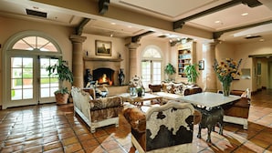 Amplia sala de estar con chimenea, sofás de cuero y una mesa de comedor.