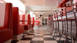 A diner with checkered flooring, red booths, and chrome bar stools. - Hotel Azucena (Huamantla)