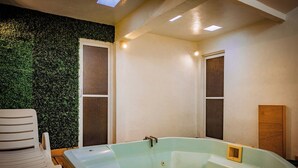A bathroom with a large bathtub, a white chair, and a green wall. - Hotel Azucena (Huamantla)