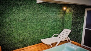 A room with a green artificial grass wall, a white lounge chair, and a light blue bathtub. - Hotel Azucena (Huamantla)