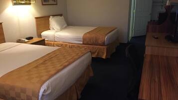 A hotel room with two beds, a desk, a chair, and a television.