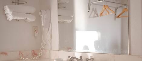 Een badkamer met een wastafel, spiegel, handdoekhouder en douche.