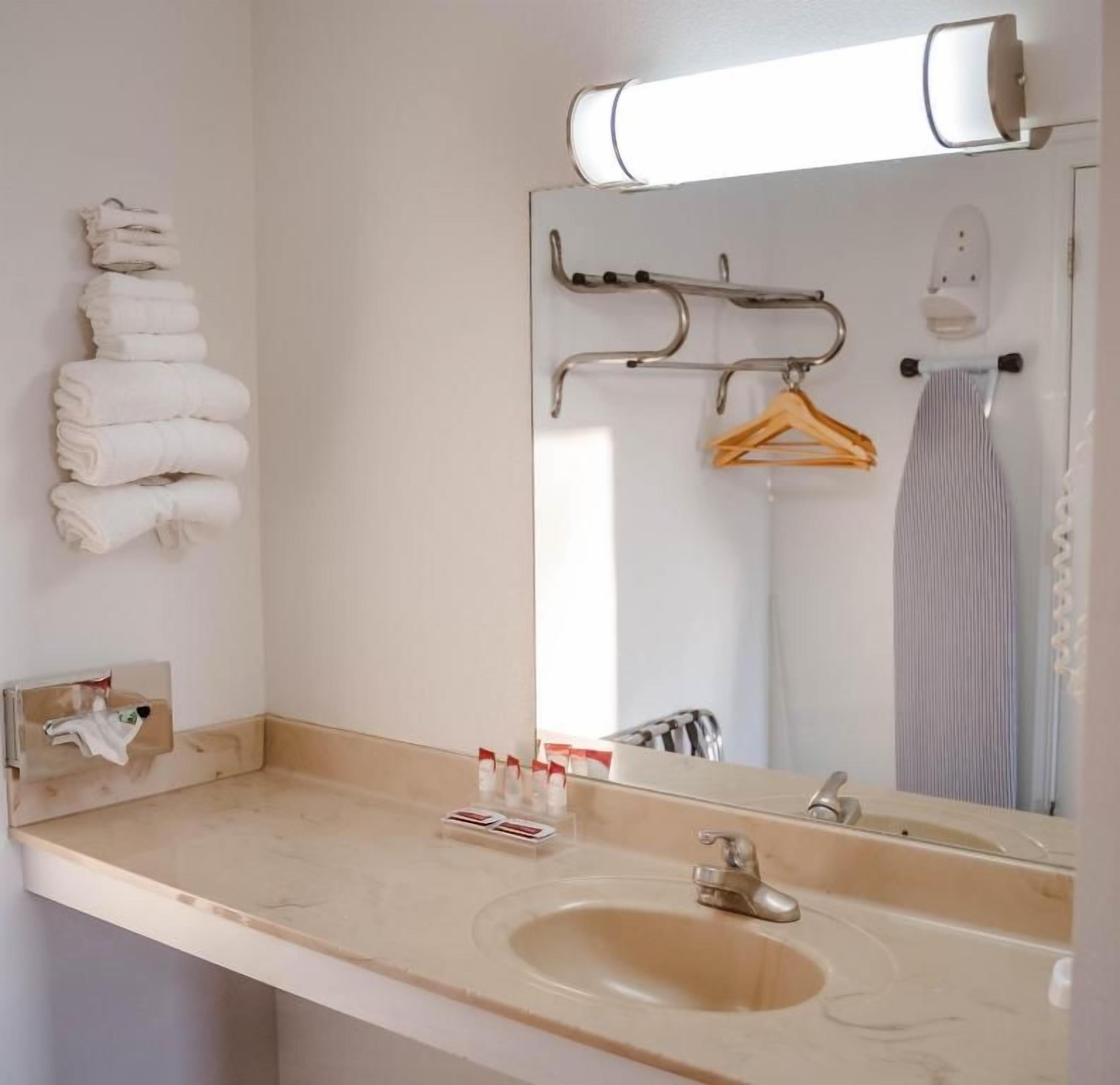 Une salle de bain équipée d’un lavabo, d’un miroir, d’un porte-serviettes et d’un étendoir à vêtements.