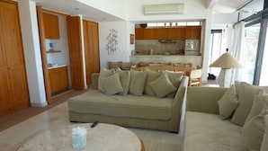 Una sala de estar moderna con un sofá color beige, una mesa de centro redonda y suelo de madera.