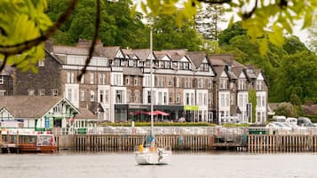 A waterfront hotel with multiple stories, a dock with a boat, and a pier with a sign.