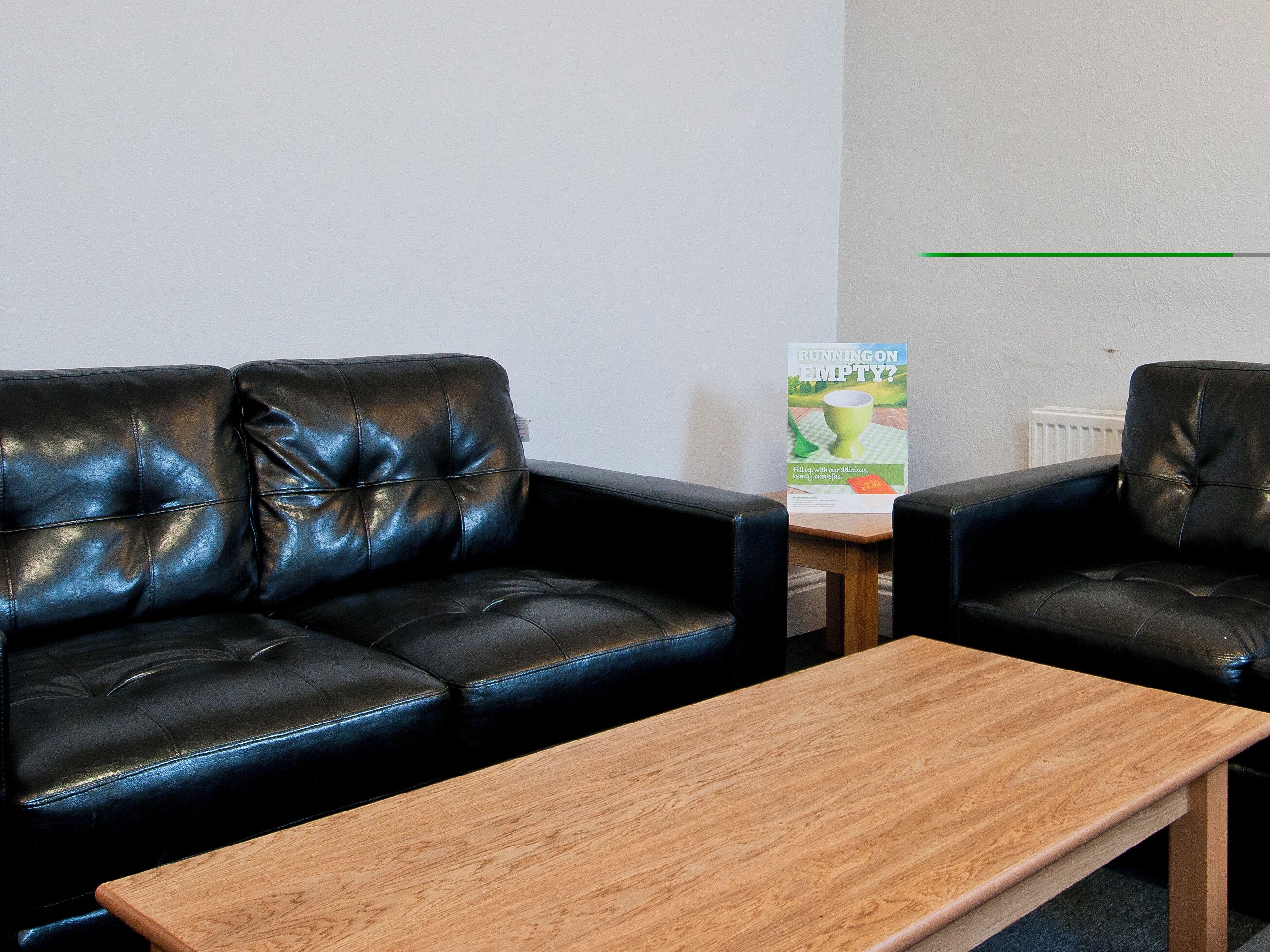 A room with two black leather sofas and a wooden coffee table.