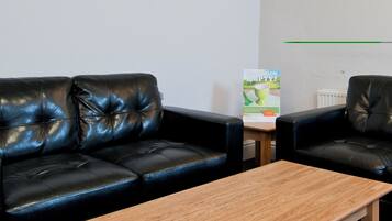 A room with two black leather sofas and a wooden coffee table.