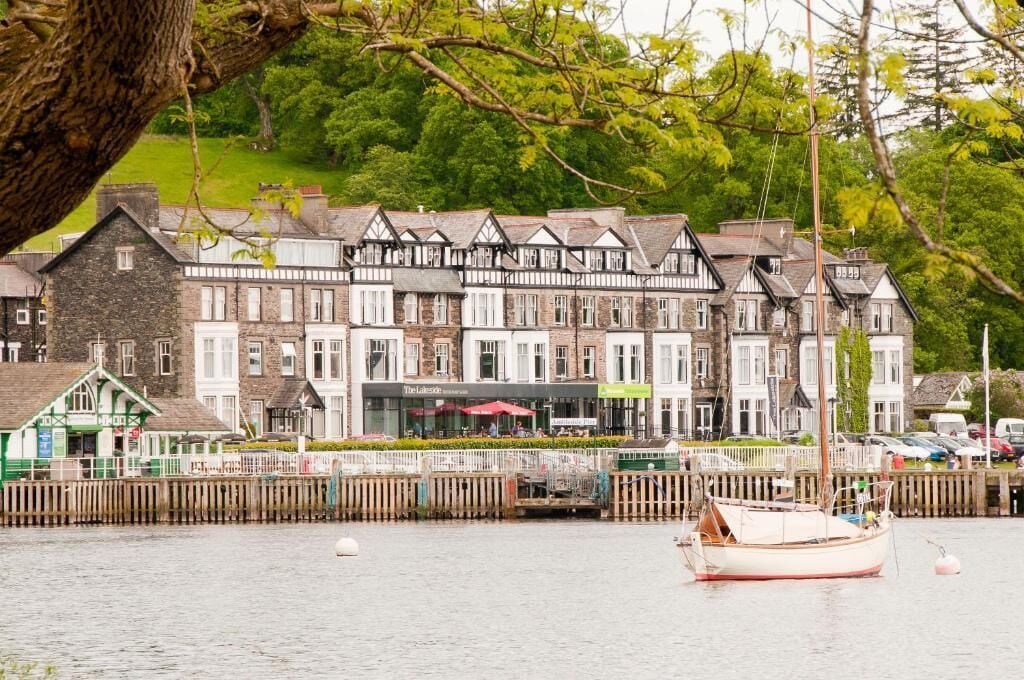 A row of traditional buildings with a waterfront view, a wooden fence, and a boat docked in the water.