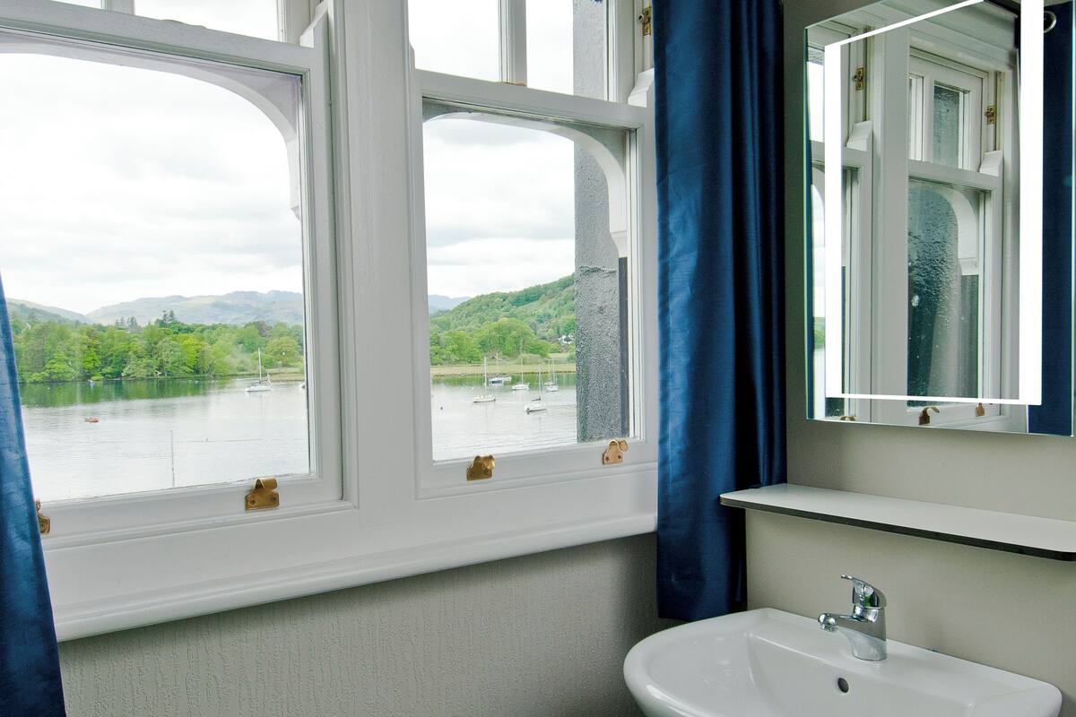 A bathroom with a white sink, a mirror, and a view of a lake with boats.
