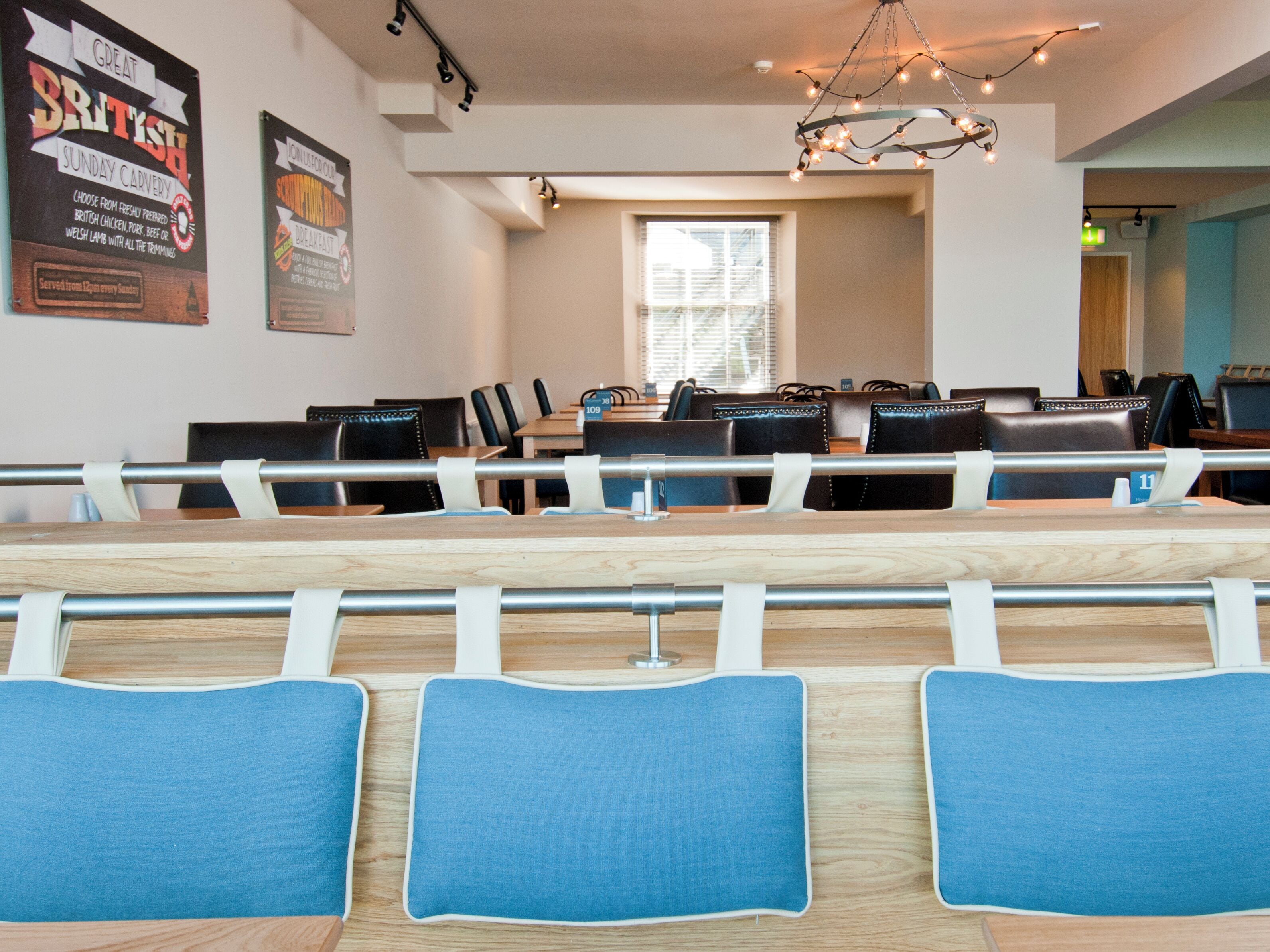 A conference room with a long table, blue cushioned chairs, and a chandelier.
