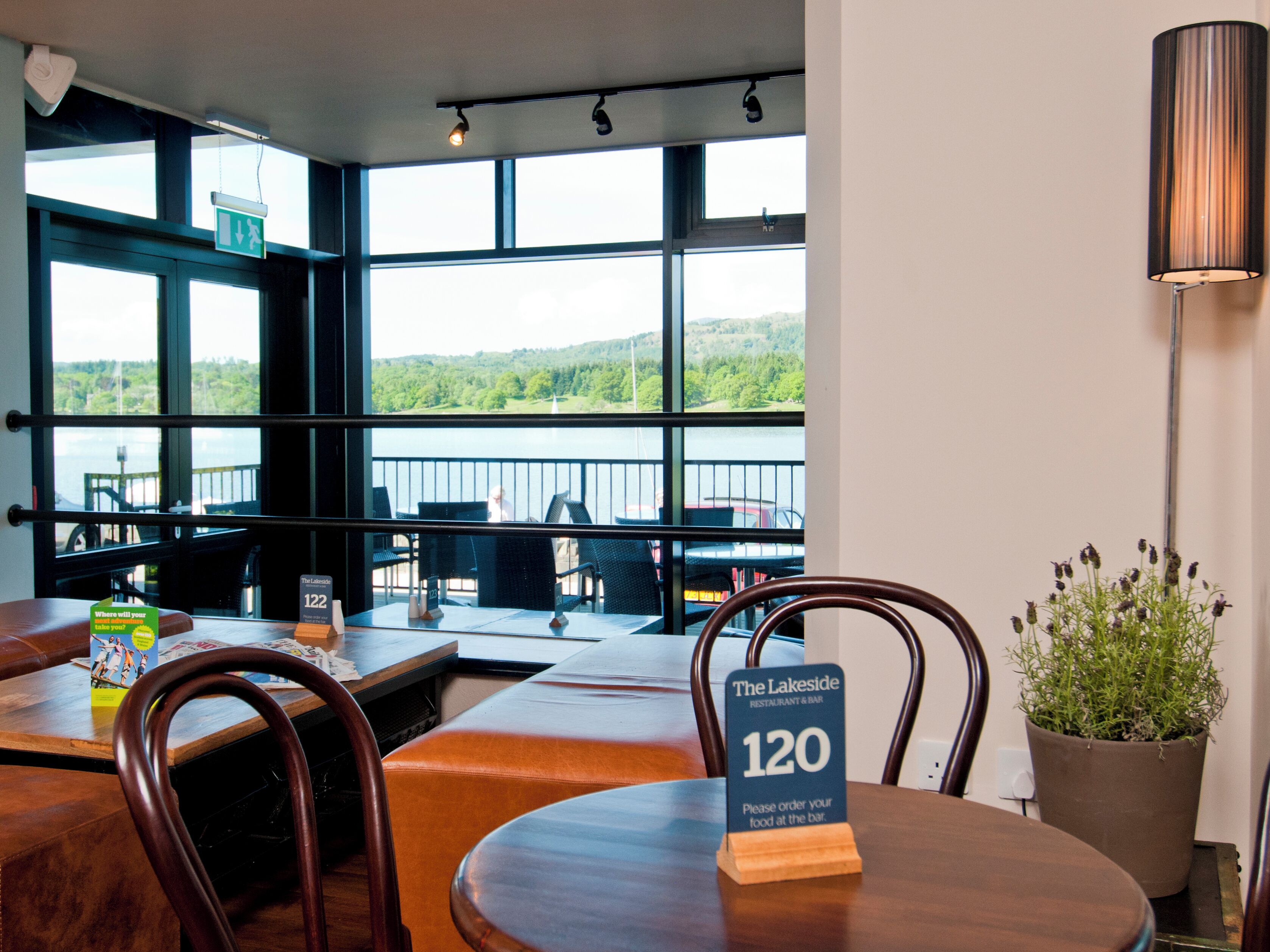 A restaurant with a view of the lake, outdoor seating, and a sign indicating table number 120.