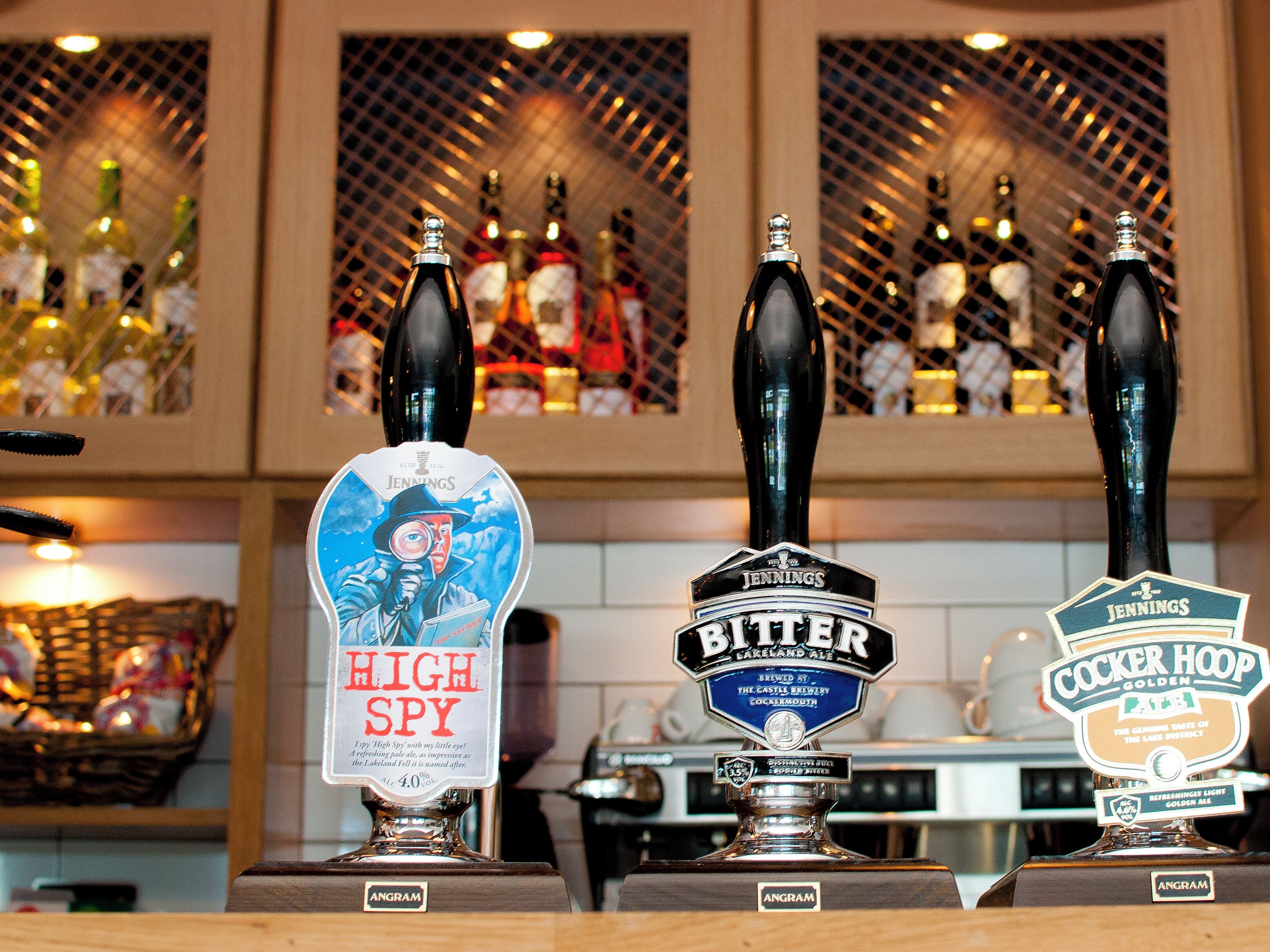 Three beer taps labeled 'High Spy', 'Bitter', and 'Cocker Hoop' in a bar setting.