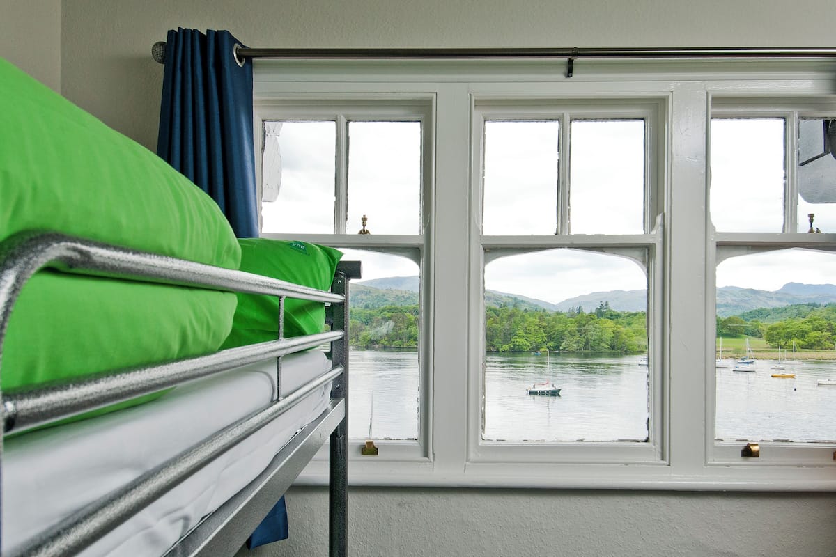 A room with bunk beds and a large window overlooking a lake with boats.