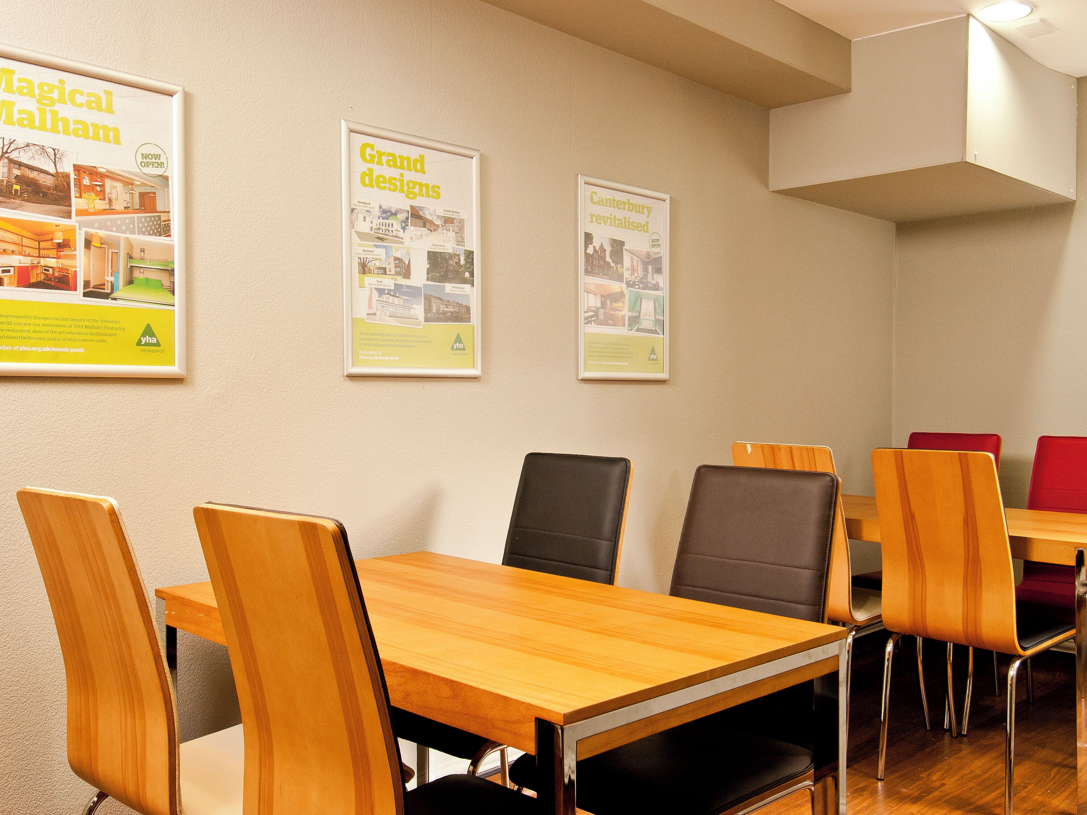 A conference room with wooden tables and chairs, posters on the wall, and a ceiling light.