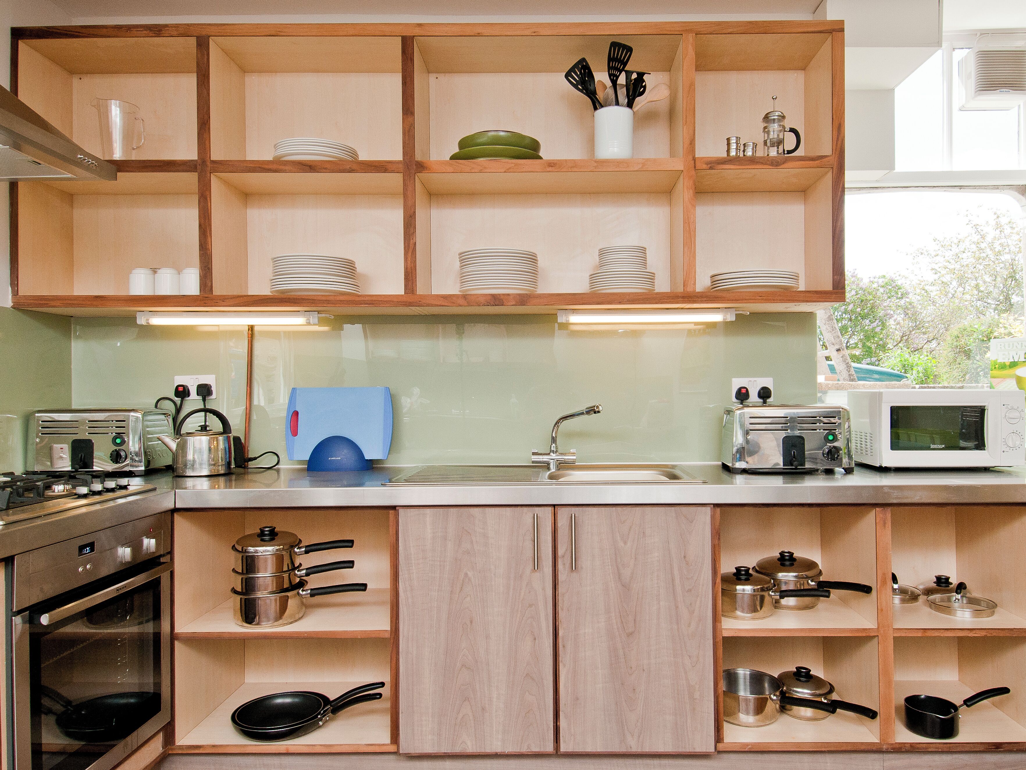 A kitchen with wooden cabinets, a microwave, a toaster, and various kitchen utensils.