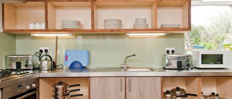 A kitchen with wooden cabinets, a microwave, a toaster, and various kitchen utensils.