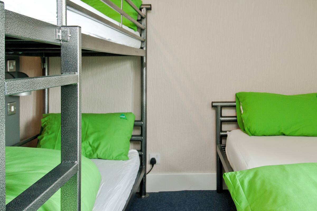 A bunk bed room with green pillows and a metal frame.