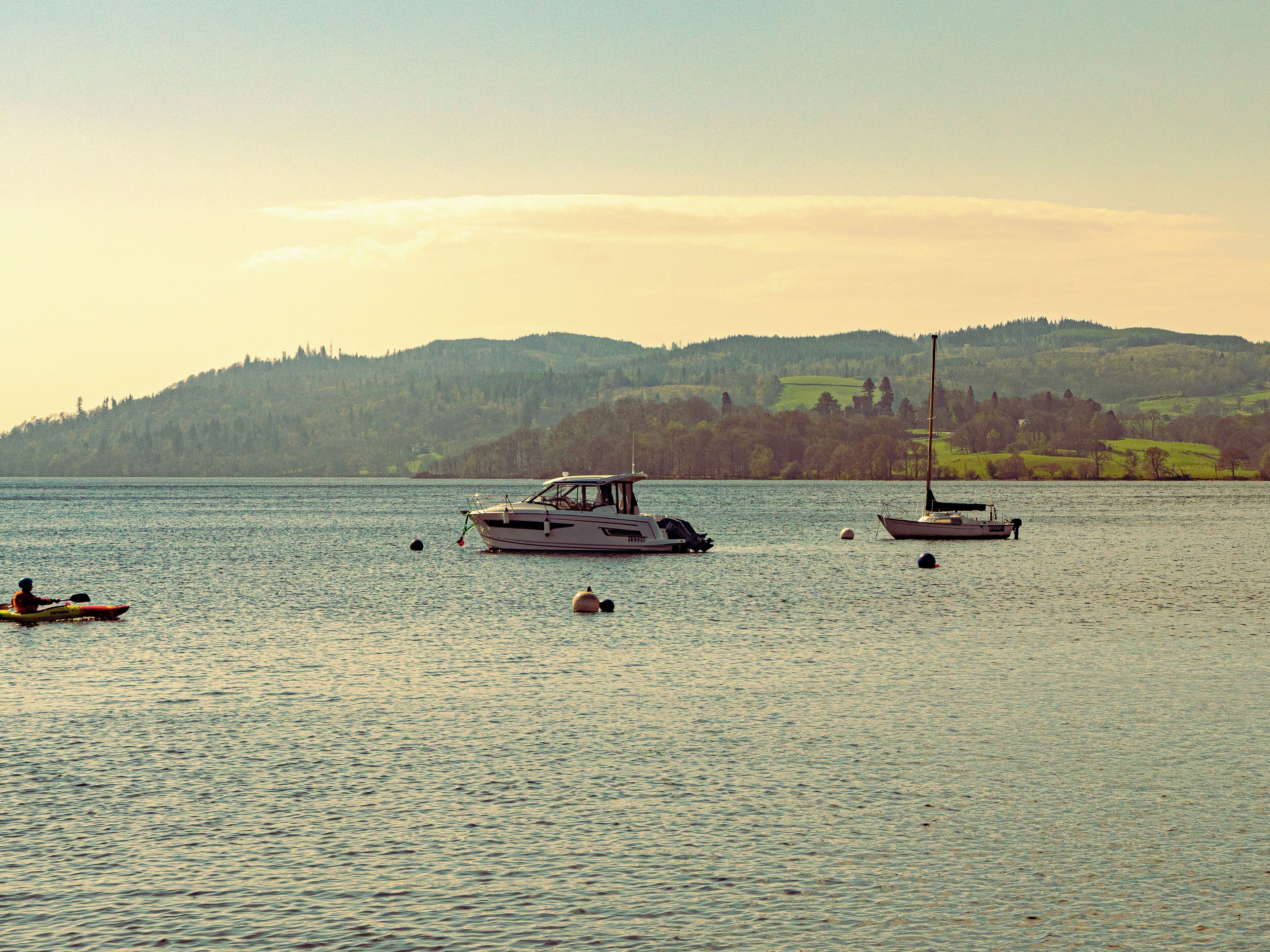 A calm lake with boats and a kayaker.