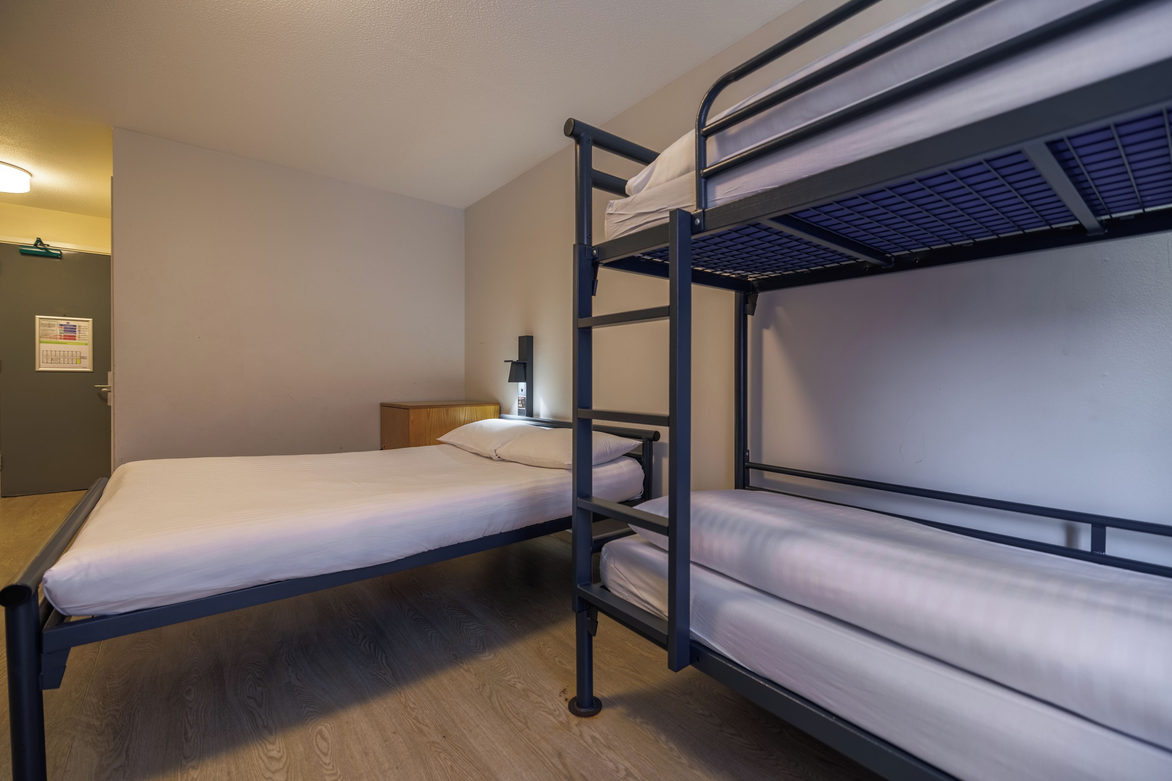 A bunk bed room with a single bed and a desk.