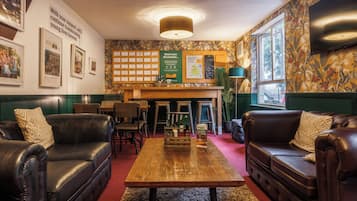 A cozy lounge area with leather sofas, a wooden coffee table, and a wall adorned with framed photos and a bulletin board.