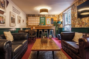 A cozy lounge area with leather sofas, a wooden coffee table, and a wall adorned with framed photos and a bulletin board. - YHA Liverpool Albert Dock - Hostel (Liverpool)