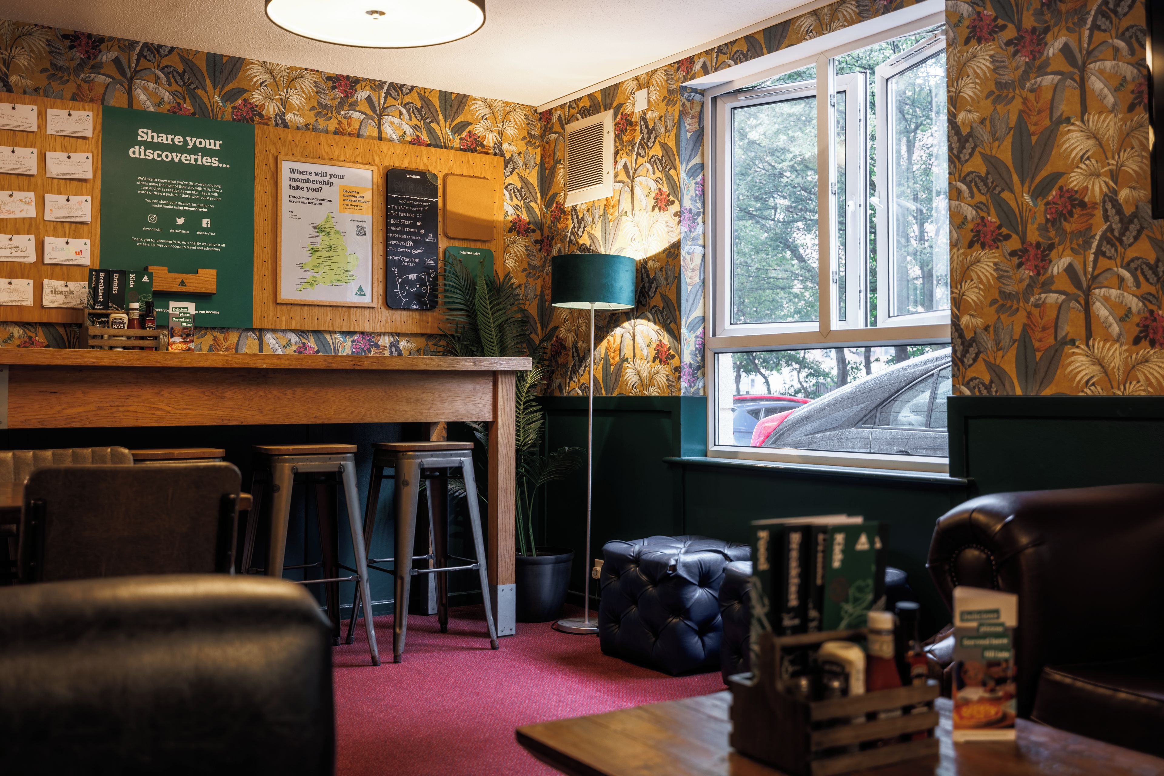 Eine gemütliche Bar mit einer Holztheke, Barhocker und einer Karte an der Wand.