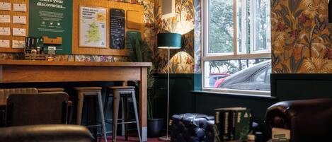 Eine gemütliche Bar mit einer Holztheke, Barhocker und einer Karte an der Wand.