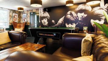 A billiards table in a room with leather seating and a large poster on the wall.