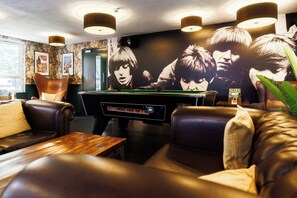 A billiards table in a room with leather seating and a large poster on the wall. - YHA Liverpool Albert Dock - Hostel (Liverpool)