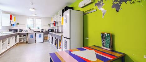 Una cucina moderna con mobili bianchi, un forno integrato e un tavolo colorato.