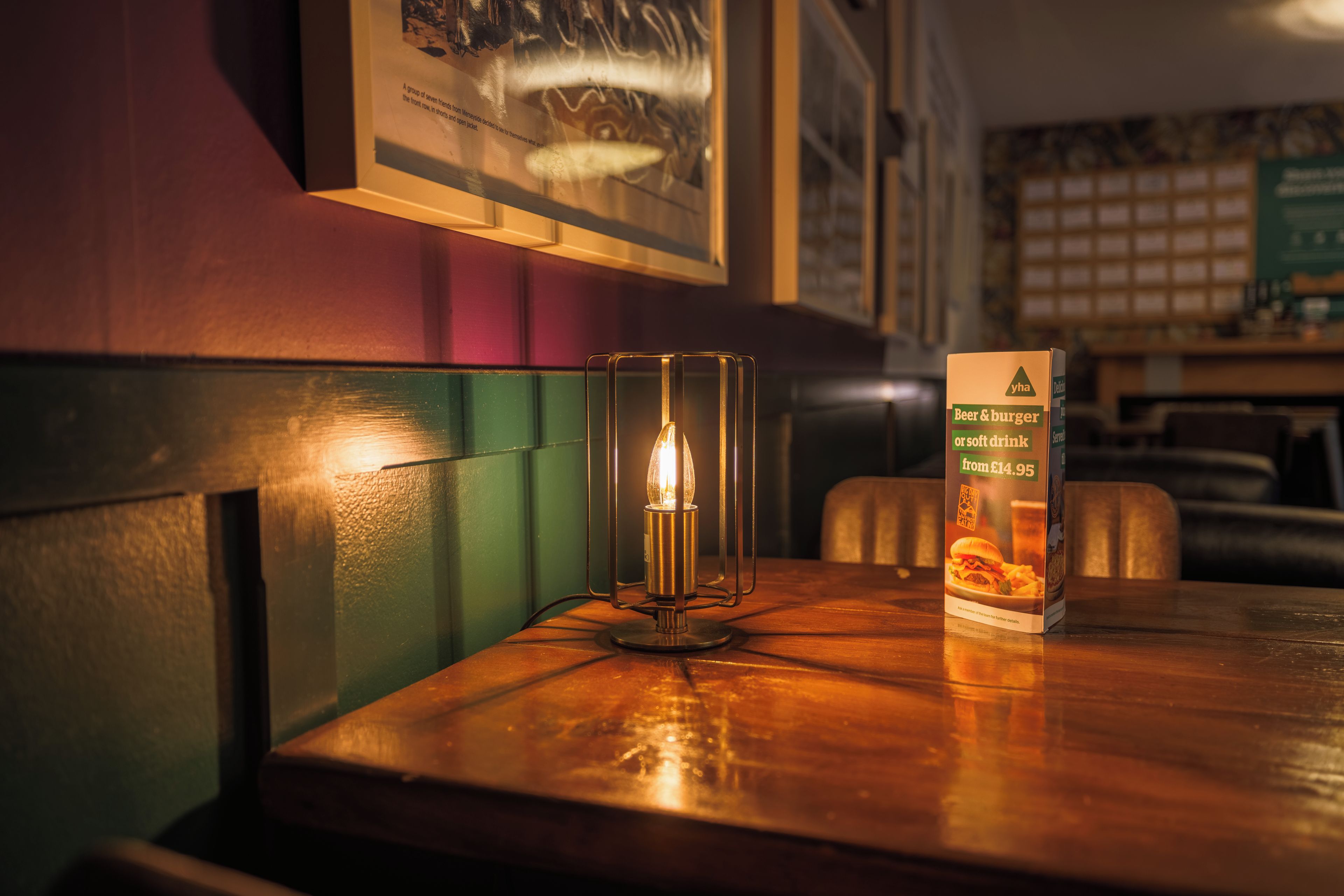 Una mesa con una vela y una caja de cerveza, hamburguesas o refrescos.