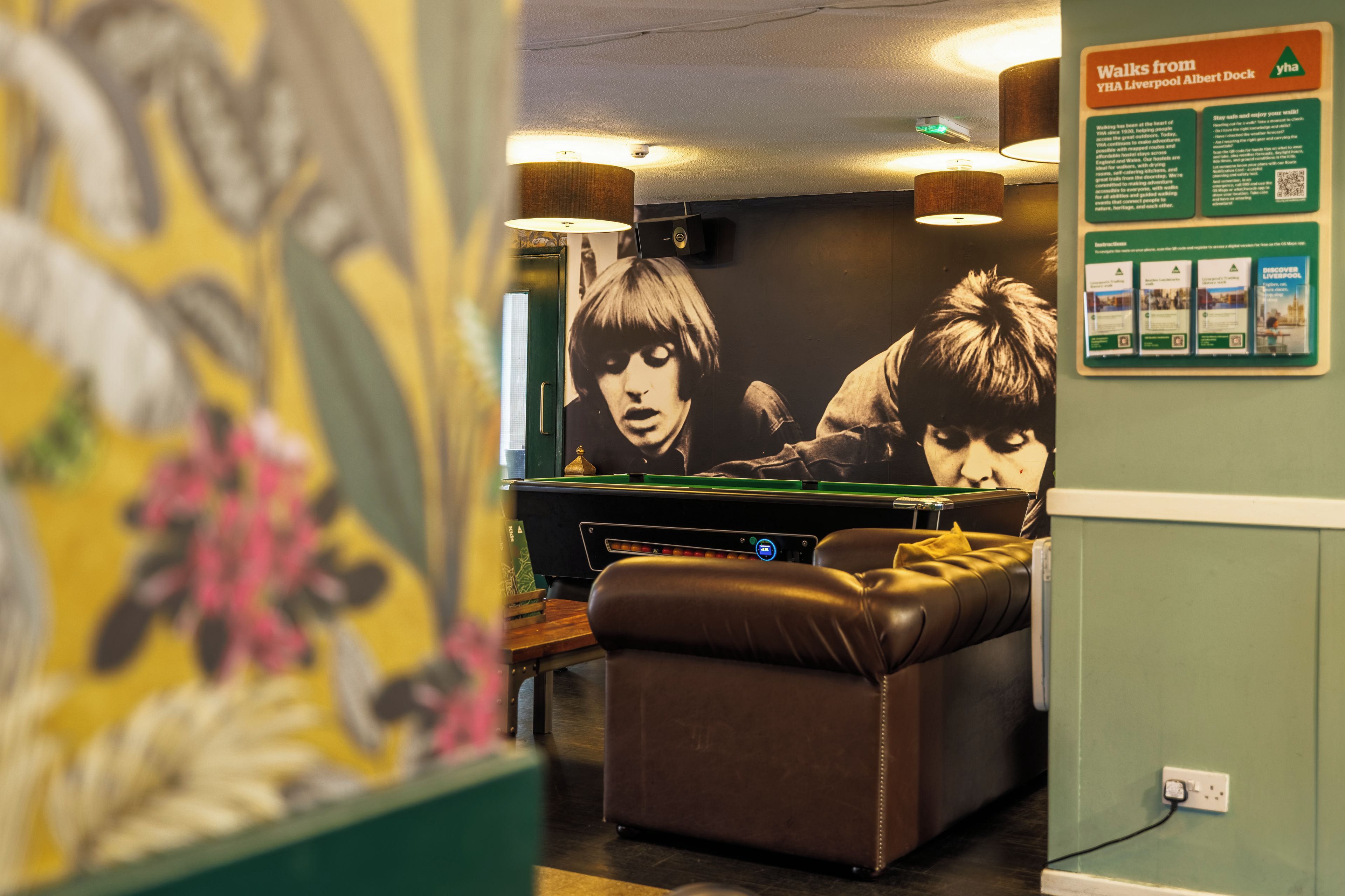 A billiards table in a room with a mural and a poster on the wall.