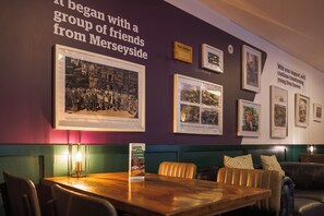 A wall with framed historical photographs and a sign about the establishment's origins. - YHA Liverpool Albert Dock - Hostel (Liverpool)