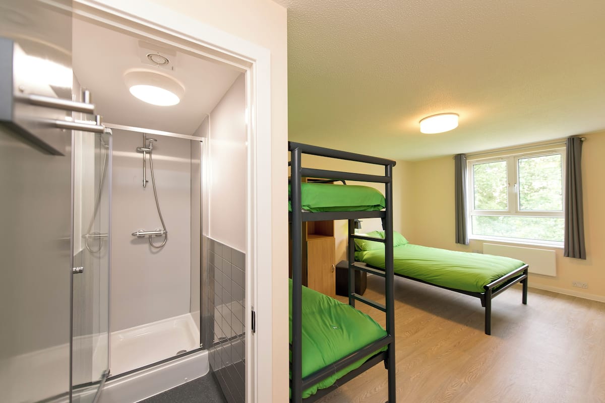 A room with a shower, bunk beds, and a window.