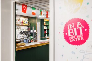 A bar area with a counter, shelves with bottles, and a sign indicating a price for food and drinks. - YHA Liverpool Albert Dock - Hostel (Liverpool)
