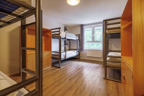 A dormitory room with bunk beds, wooden flooring, and a window with a view of greenery. - YHA Liverpool Albert Dock - Hostel (Liverpool)