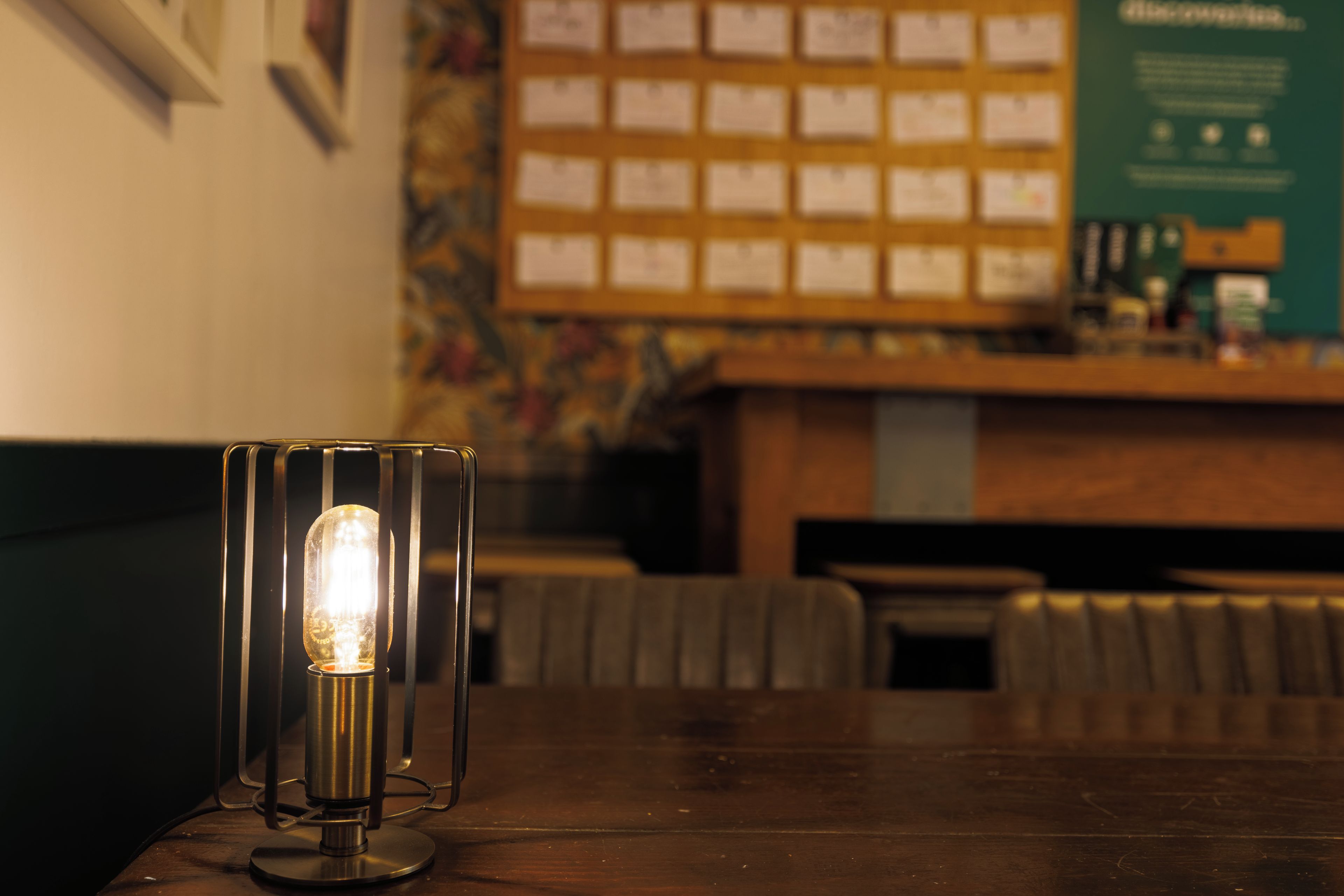 A table with a vintage-style lamp and a menu board in the background.