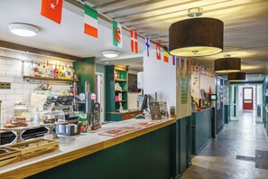 Eine Bar mit einer Theke, Regalen voller Flaschen und einer Beschilderung, die Bier und Burger anbietet.