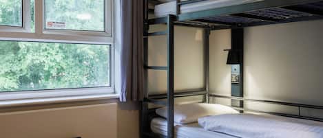 Une chambre avec un lit superposé, une fenêtre, une prise de courant et un panneau indiquant qu'il est interdit de fumer.