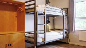 Een slaapkamer met een stapelbed, een houten garderobe en een raam met gordijnen.