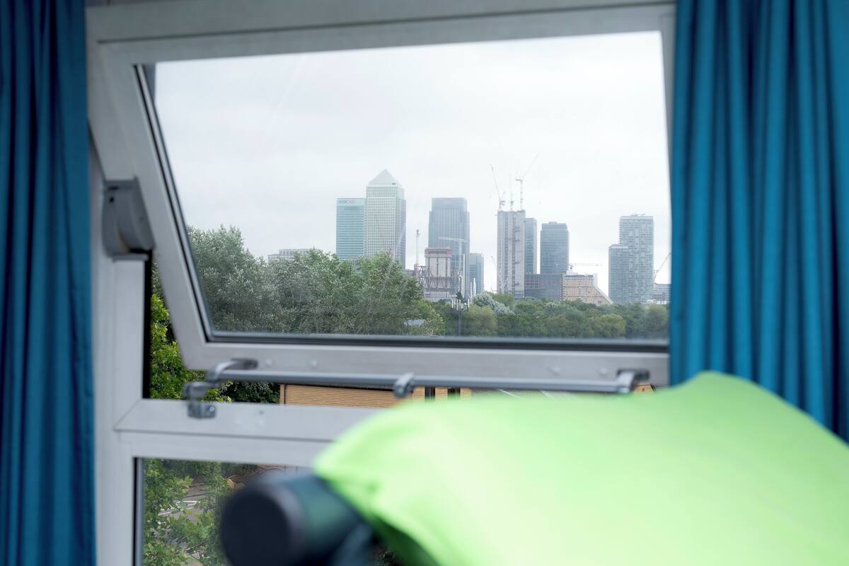 A window with a view of a city skyline, including several high-rise buildings and trees.