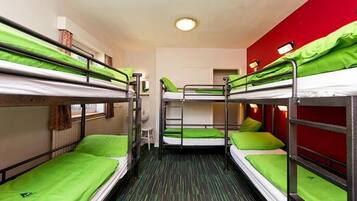 A dormitory room with bunk beds, a small desk, and a chair.