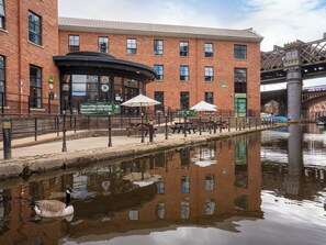 A riverside building with outdoor seating and a duck swimming in the water. - YHA Manchester - Hostel (Manchester)