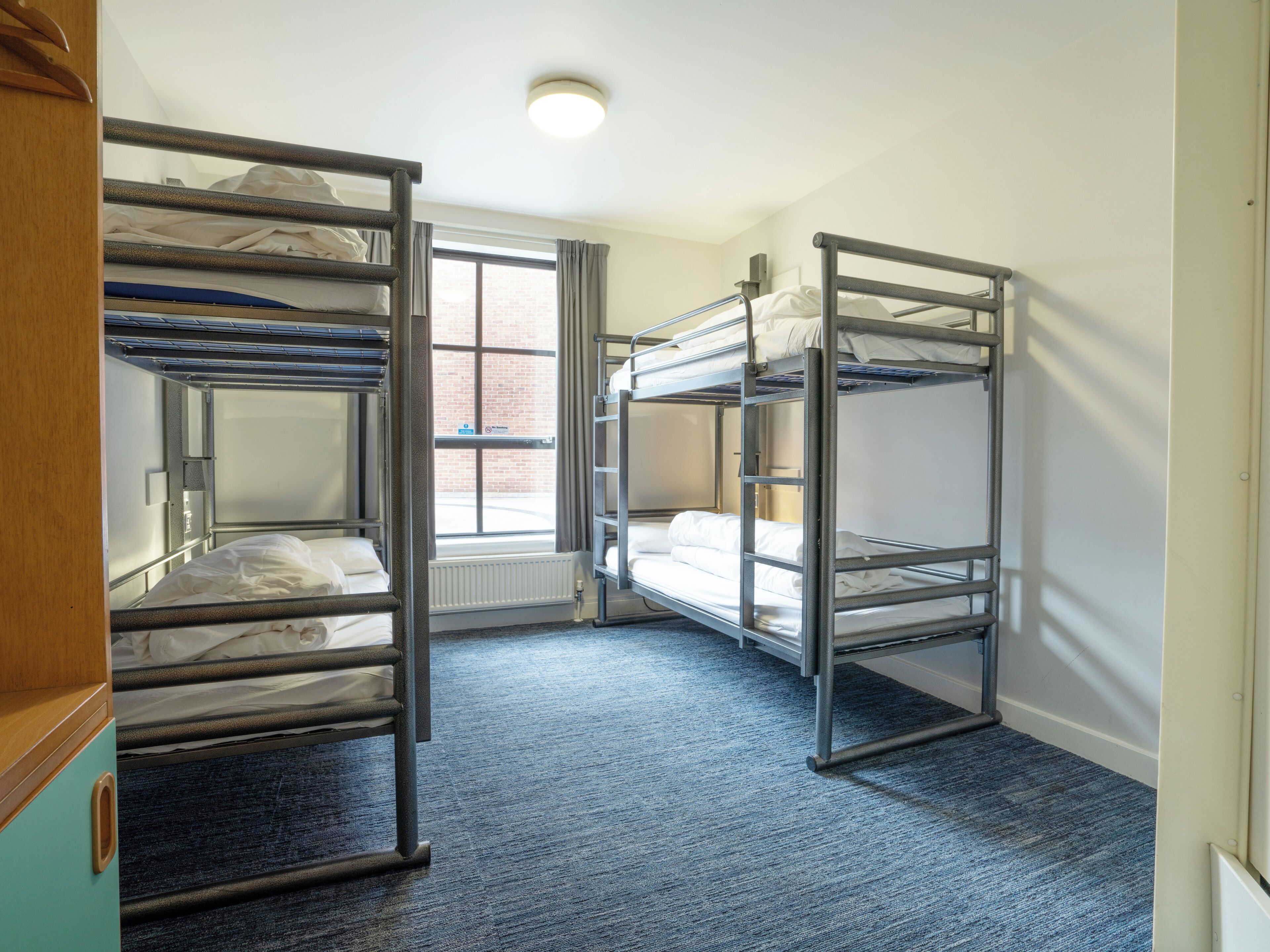 Une chambre avec des lits superposés, une fenêtre avec des rideaux et un radiateur.