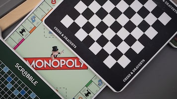 A Monopoly board game with a chess and draughts board on top.